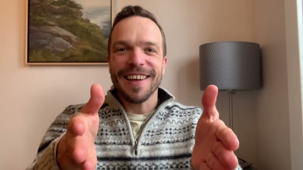 A man giving the thumbs up sign in front of a painting.