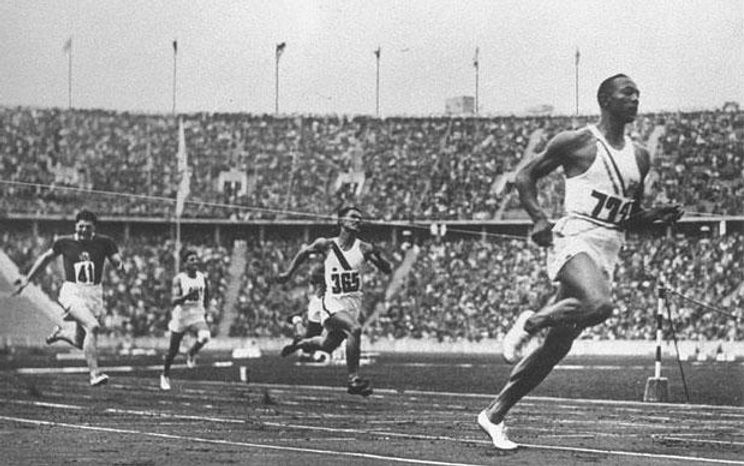 A black and white photo of men running on a track.