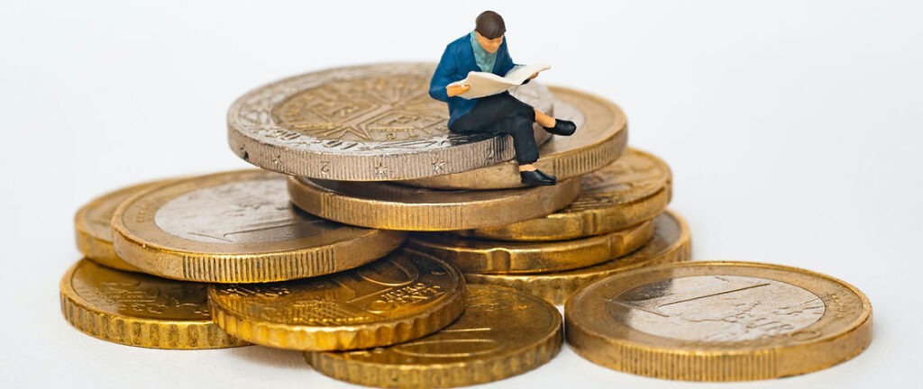 A small toy figure sitting on top of some gold coins.