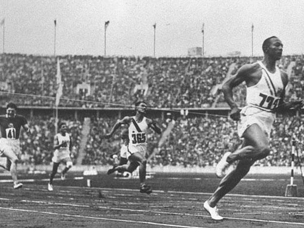 A black and white photo of men running on a track.