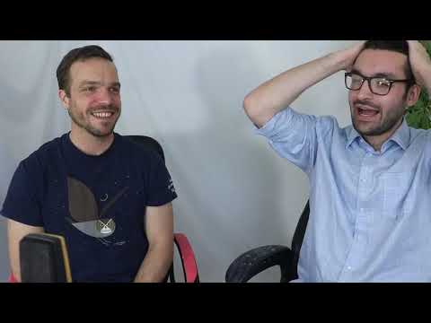 Two men sitting in a chair and one is holding his hand up to the side of his head.