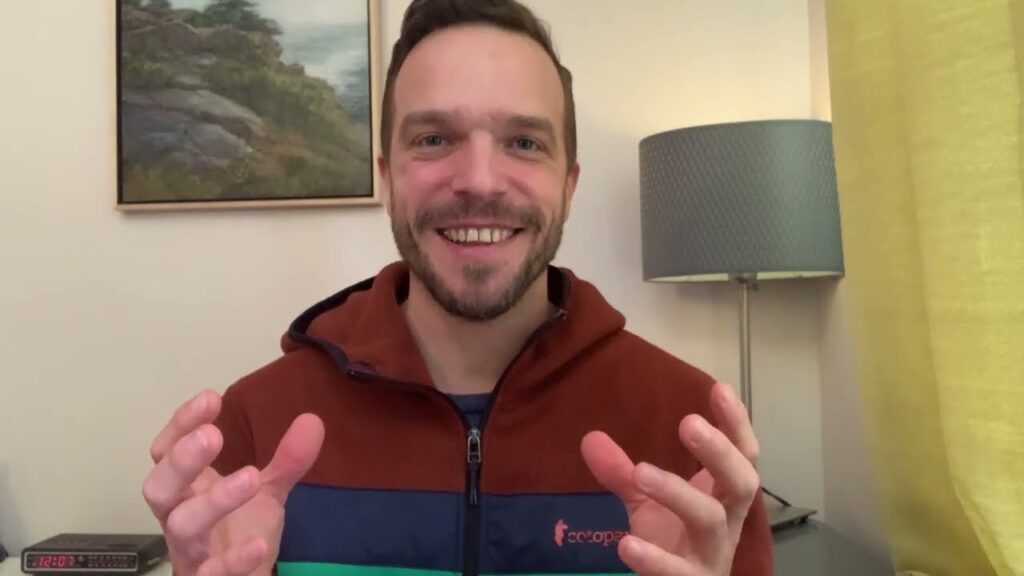 A man in a red and blue jacket smiling.