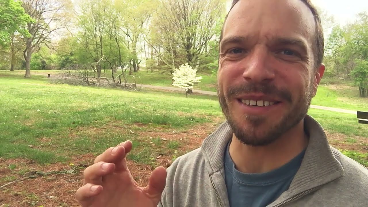 A man standing in the grass with his hands up.