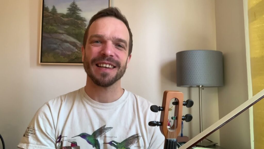 A man smiles while holding his guitar.