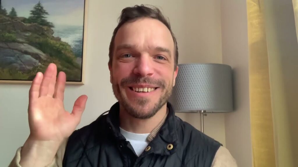 A man smiling and waving at the camera.