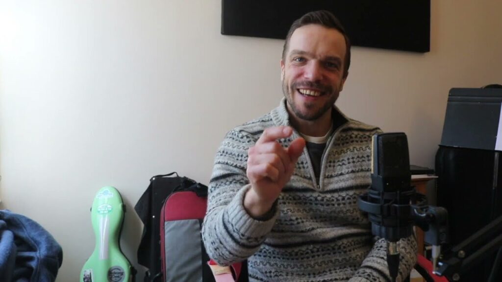 A man sitting in front of a microphone and holding up his finger.