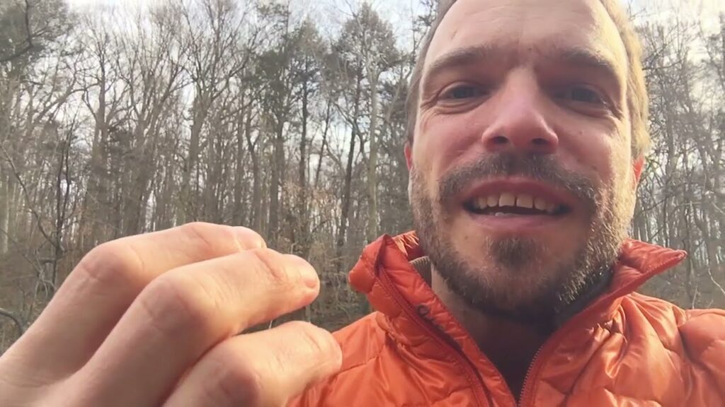 A man holding something in his hand while wearing an orange jacket.