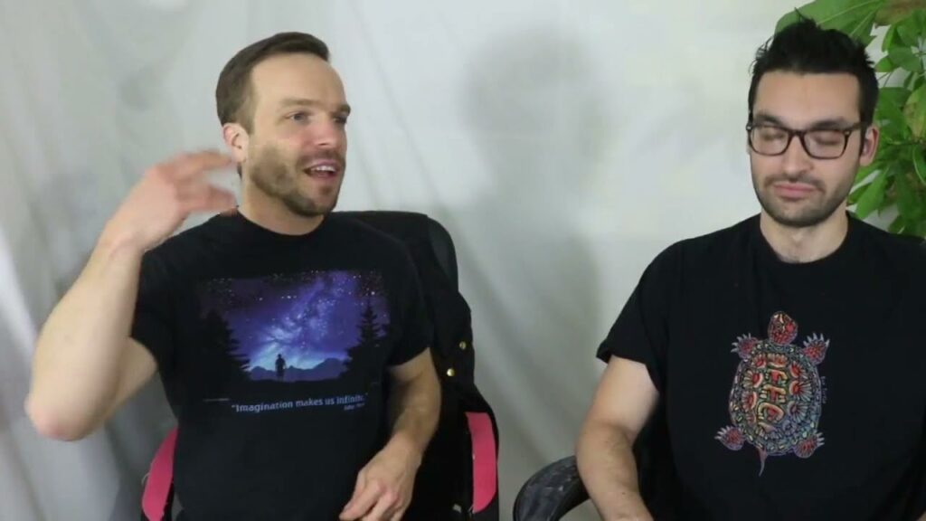 Two men sitting in a chair talking to each other.