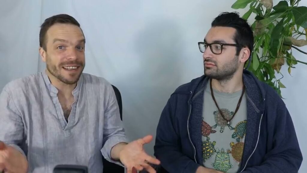 Two men sitting in front of a wall.