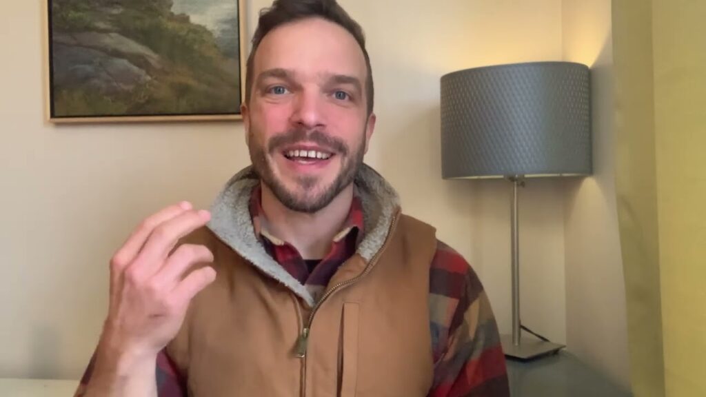 A man in a brown vest is smiling