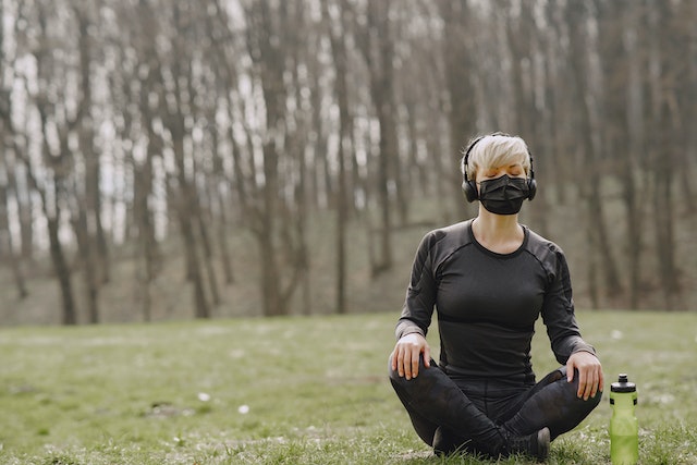 A woman sitting in the grass wearing headphones.