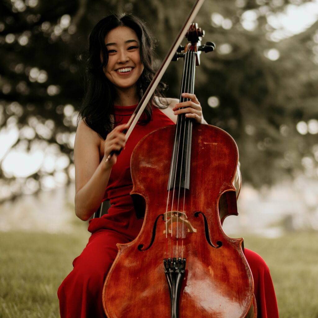 A woman in red dress holding a cello.