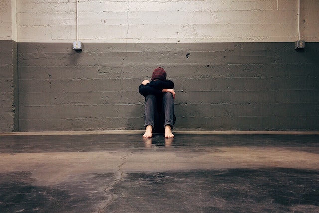 A person sitting on the ground with their head down.