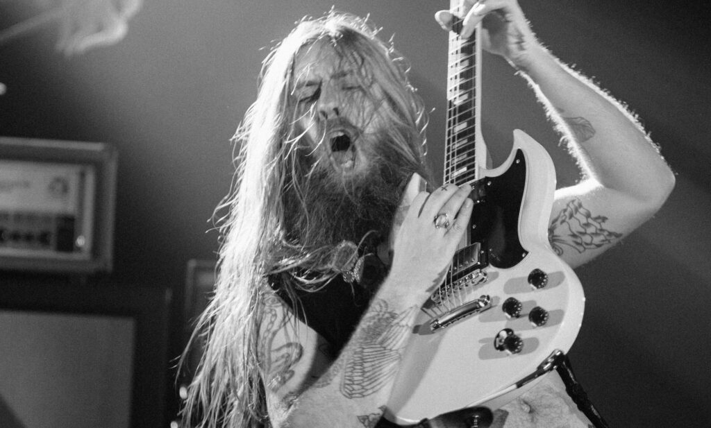 A man with long hair and beard holding a guitar.