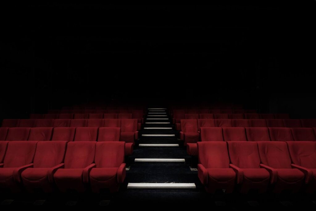 A row of red seats in front of a black wall.