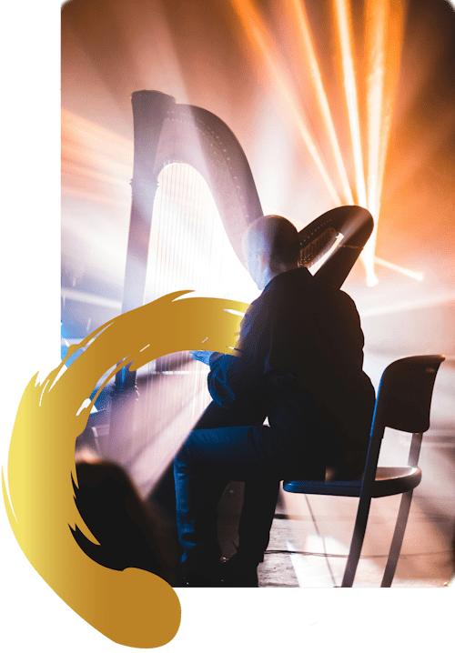 Man playing harp under stage lights.