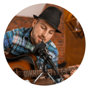 A man in plaid shirt and hat playing guitar.